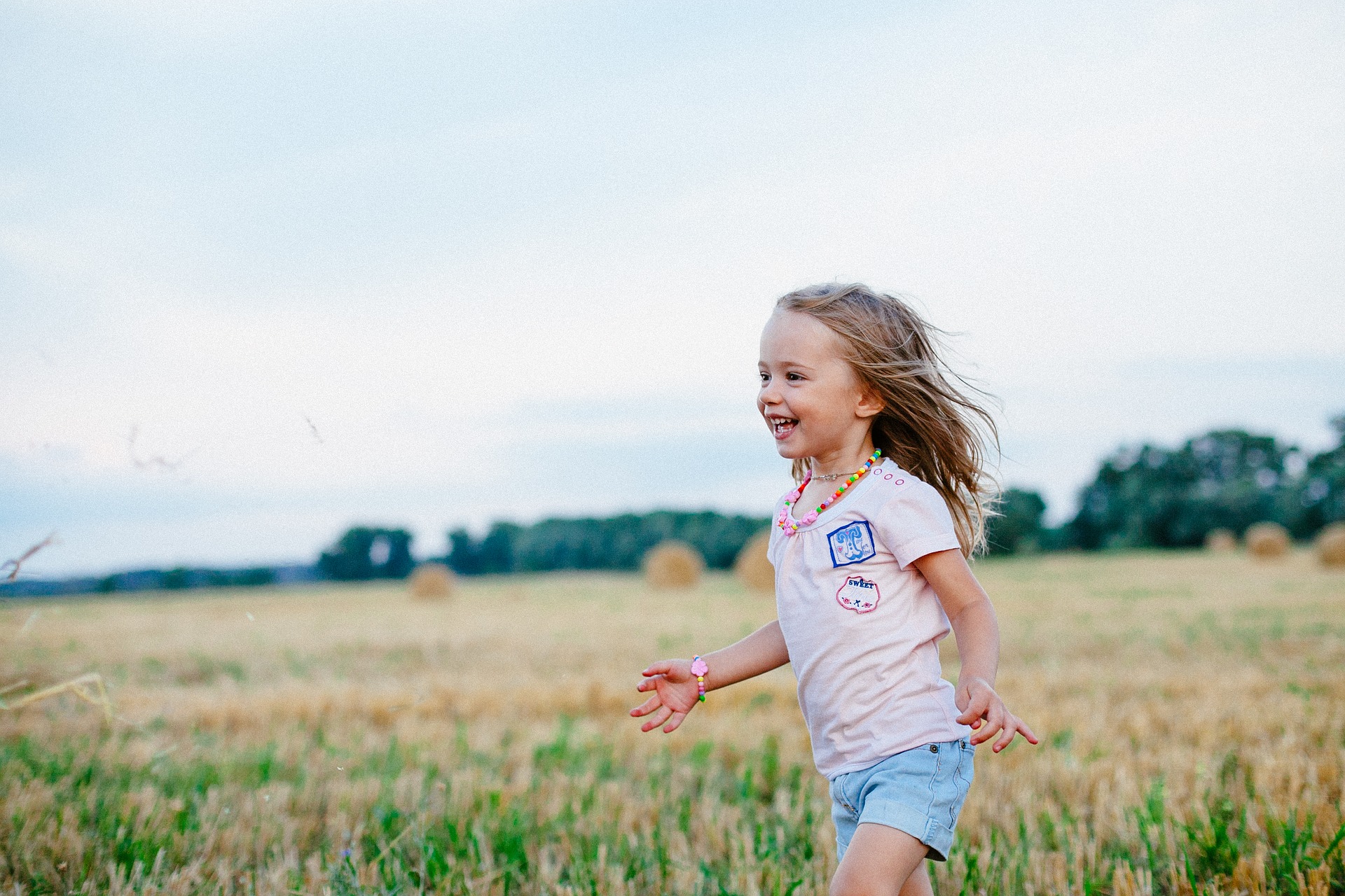 Niña sonriente corriendo por el campo