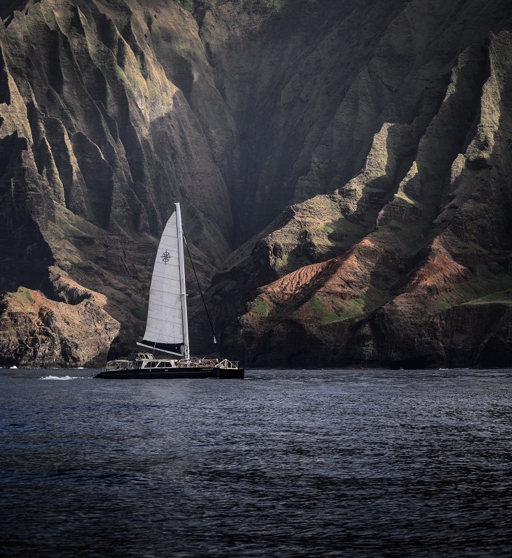 Barco de vela navegando junto a un acantilado