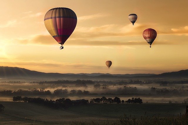 Paisaje con globos Paisaje natural al atardecer o amanecer con varios globos de aire caliente en el horizonte.