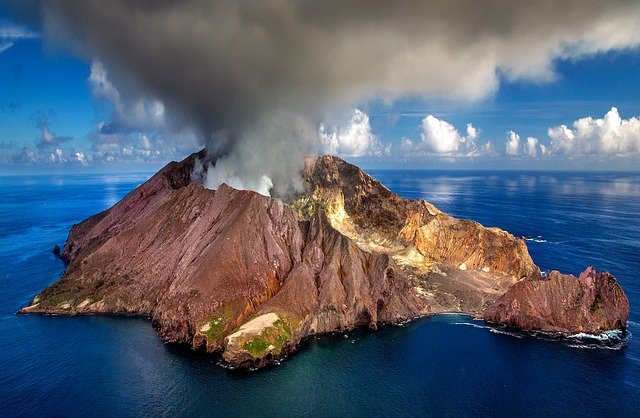 Cráter en Nueva Zelanda En la imagen aparece un volcán en erupción en una isla en mitad del océano.