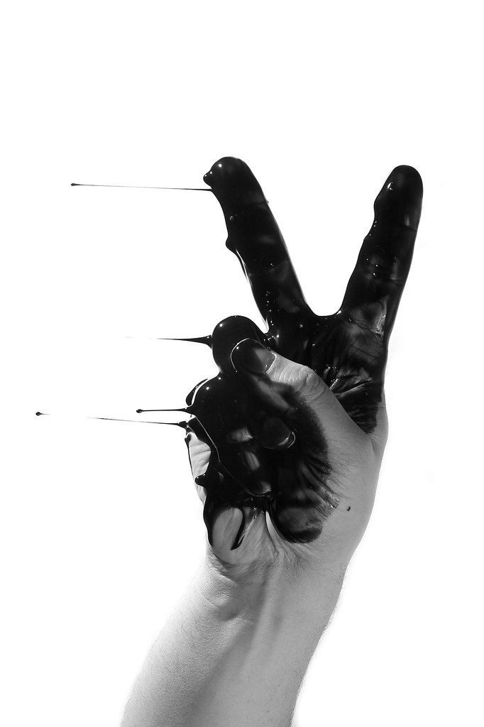 Dedos haciendo el símbolo de la paz manchados de aceite negro