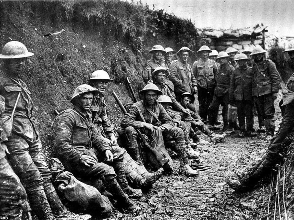 Casi veinte soldados de la prmiera guerra mundial posan sentados y de pie para una foto en una trinchera.