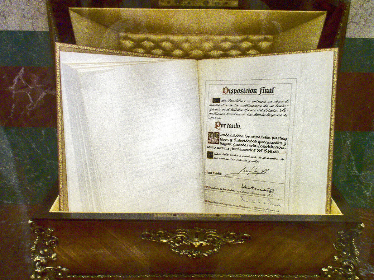 Un ejemplar de la Constitución Española abierto en una caja de madera. 