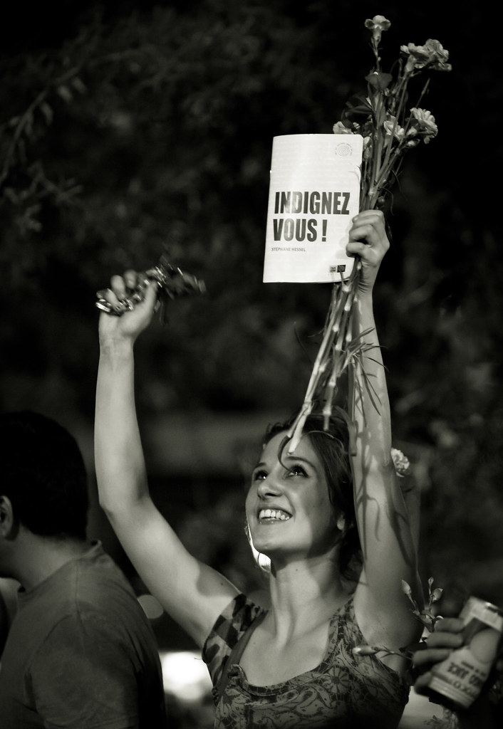 Una chica en una manifestación sostiene un ejemplar del libro ¡Indignaos! en francés