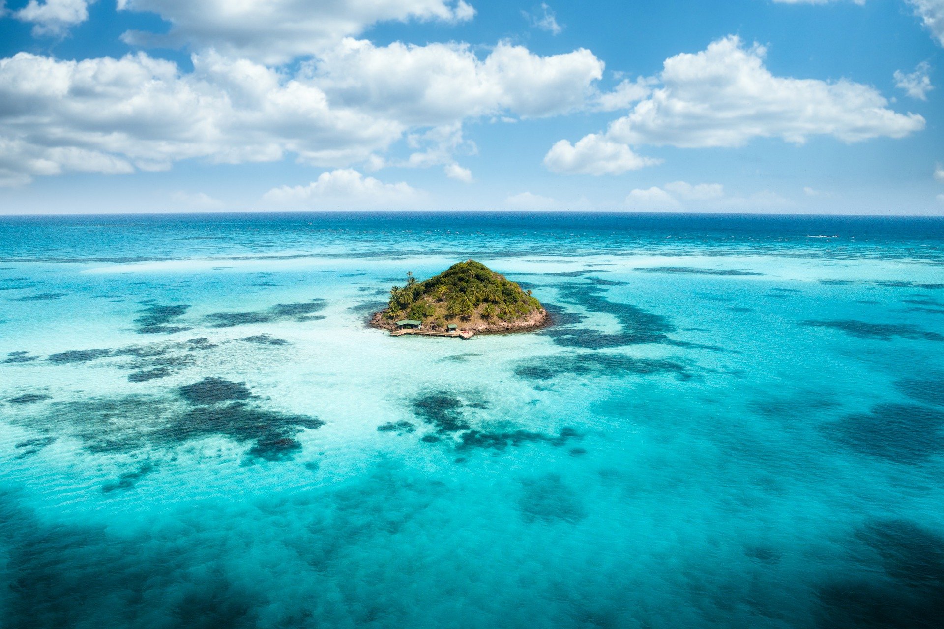 Una isla en medio del océano de aguas azul turquesa.