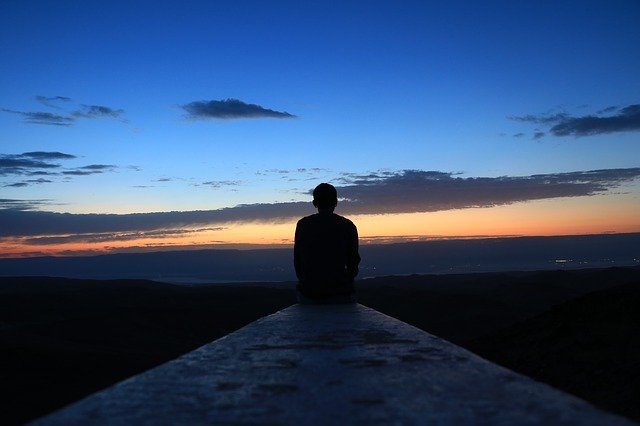 Hombre sentado observando el amanecer