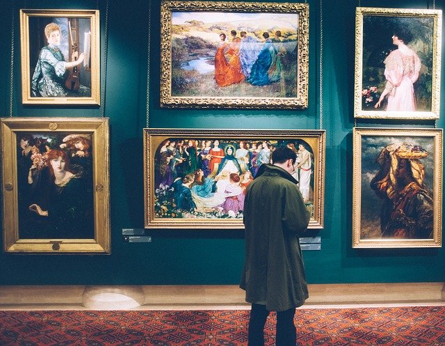 Hombre observando varios cuadros en un museo