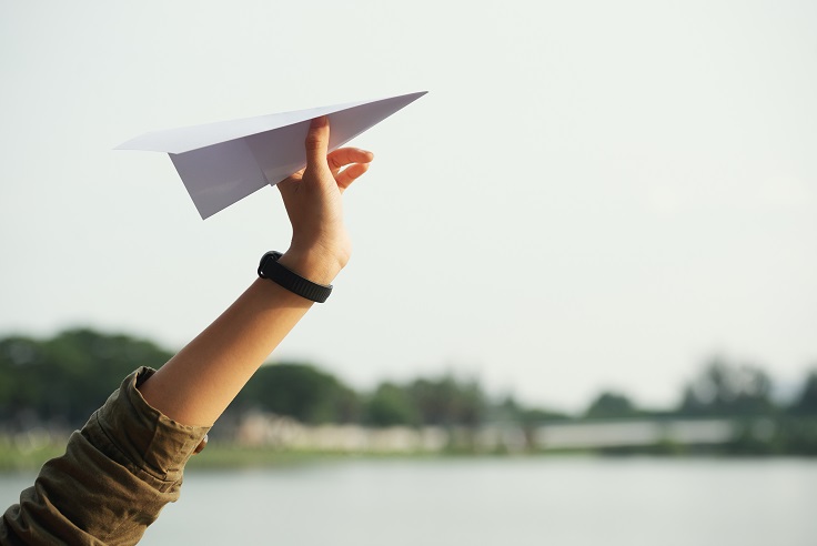 Viaje Viaje. Una mano sujeta un avión de papel.