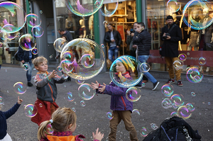 Niños jugando con pompas de jabón en la calle.