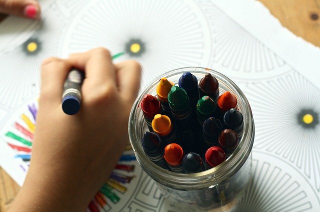 Fotografia de una mano pintando con ceras un dibujo de mandalas