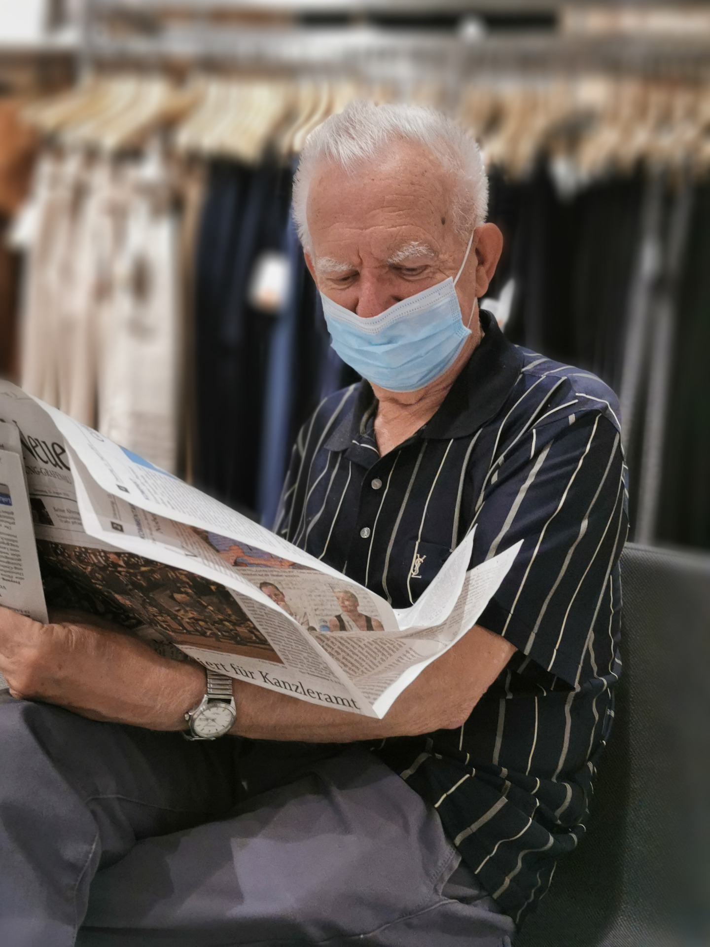 Un hombre mayor con mascarilla leyendo el periódico